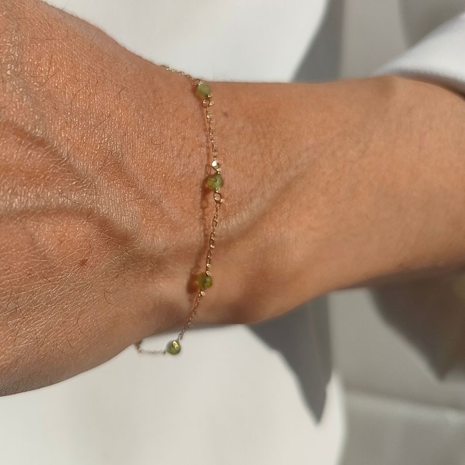 Pulsera de oro 18k con piedras naturales peridot mostrada en muñeca de modelo